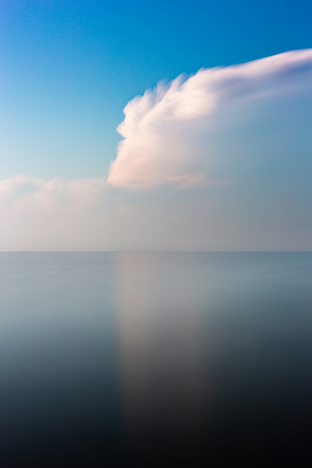 calm sea under clear blue sky and white clouds