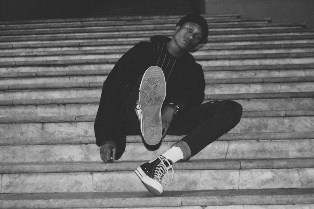 grayscale photography of man sitting on stairs