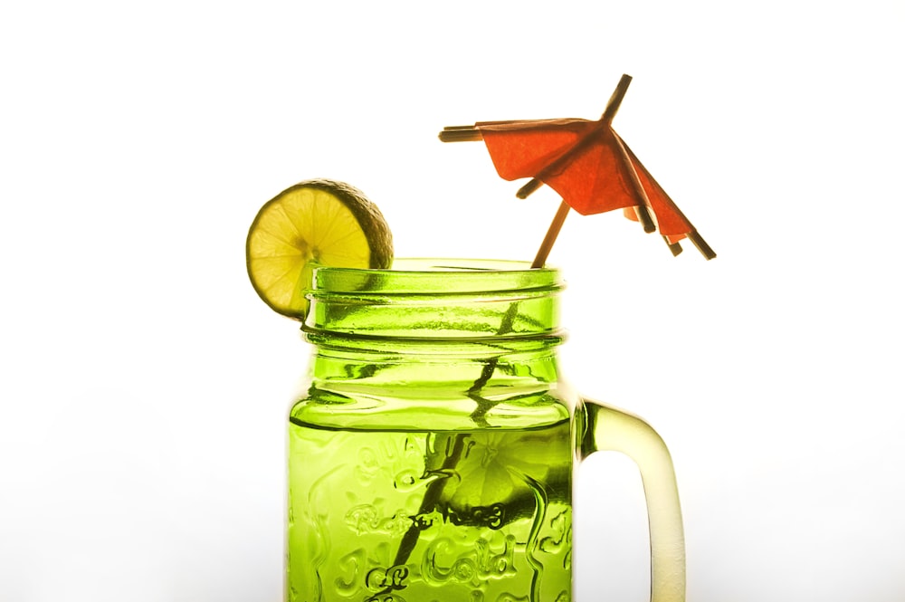 lime juice in green-tinted mason jar mug with cocktail umbrella