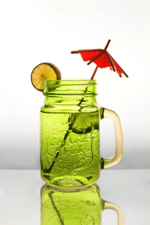 A bright cocktail jar with a straw and tropical flowers on a wooden surface