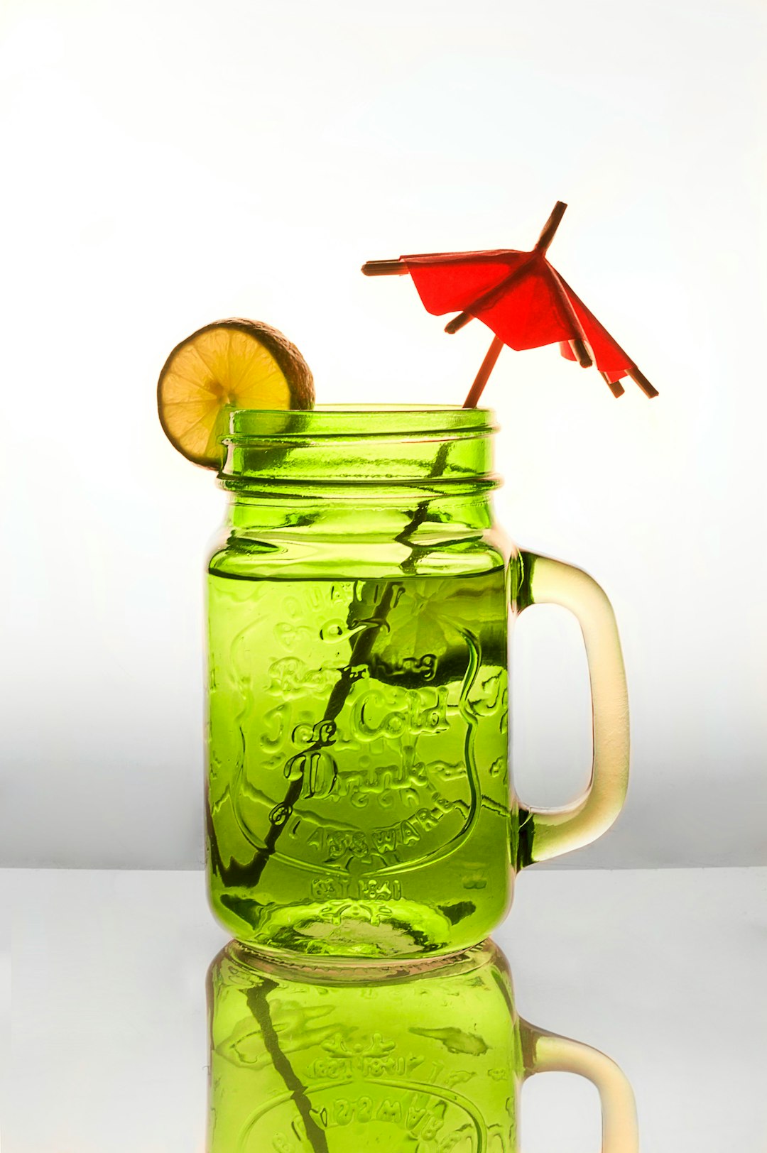 water in clear glass jar with sliced lemon and red umbrella stick