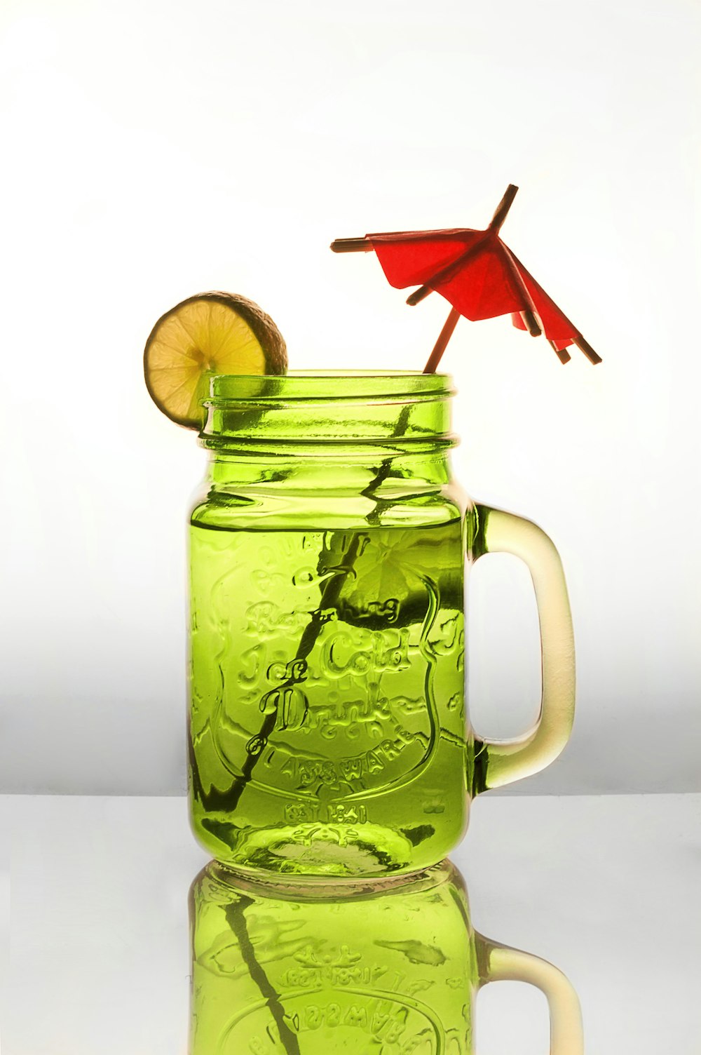 water in clear glass jar with sliced lemon and red umbrella stick