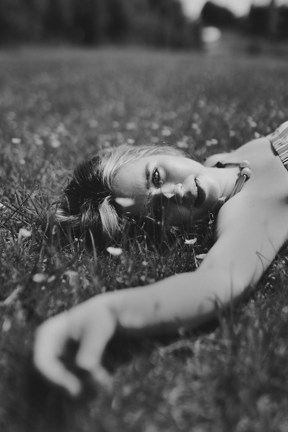 Photo en niveaux de gris d’une femme allongée sur l’herbe