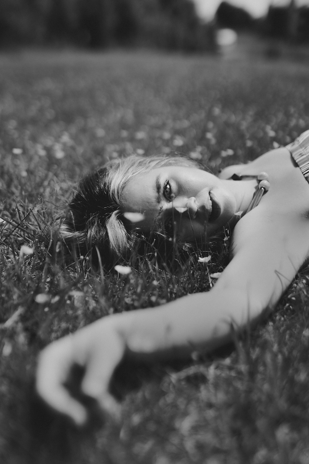 grayscale photo of woman lying on grass