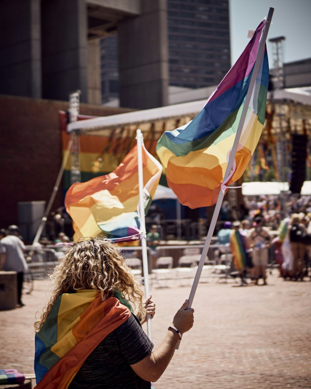 shallow focus photo of person holding yellow, orange, and blue flag