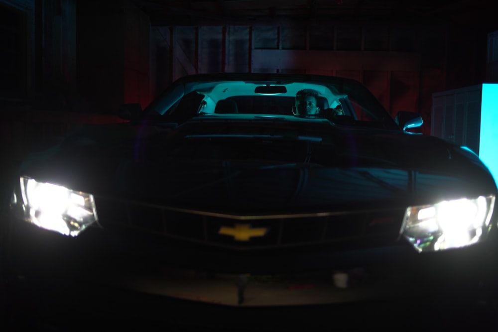 man sitting in grey Chevrolet Camaro