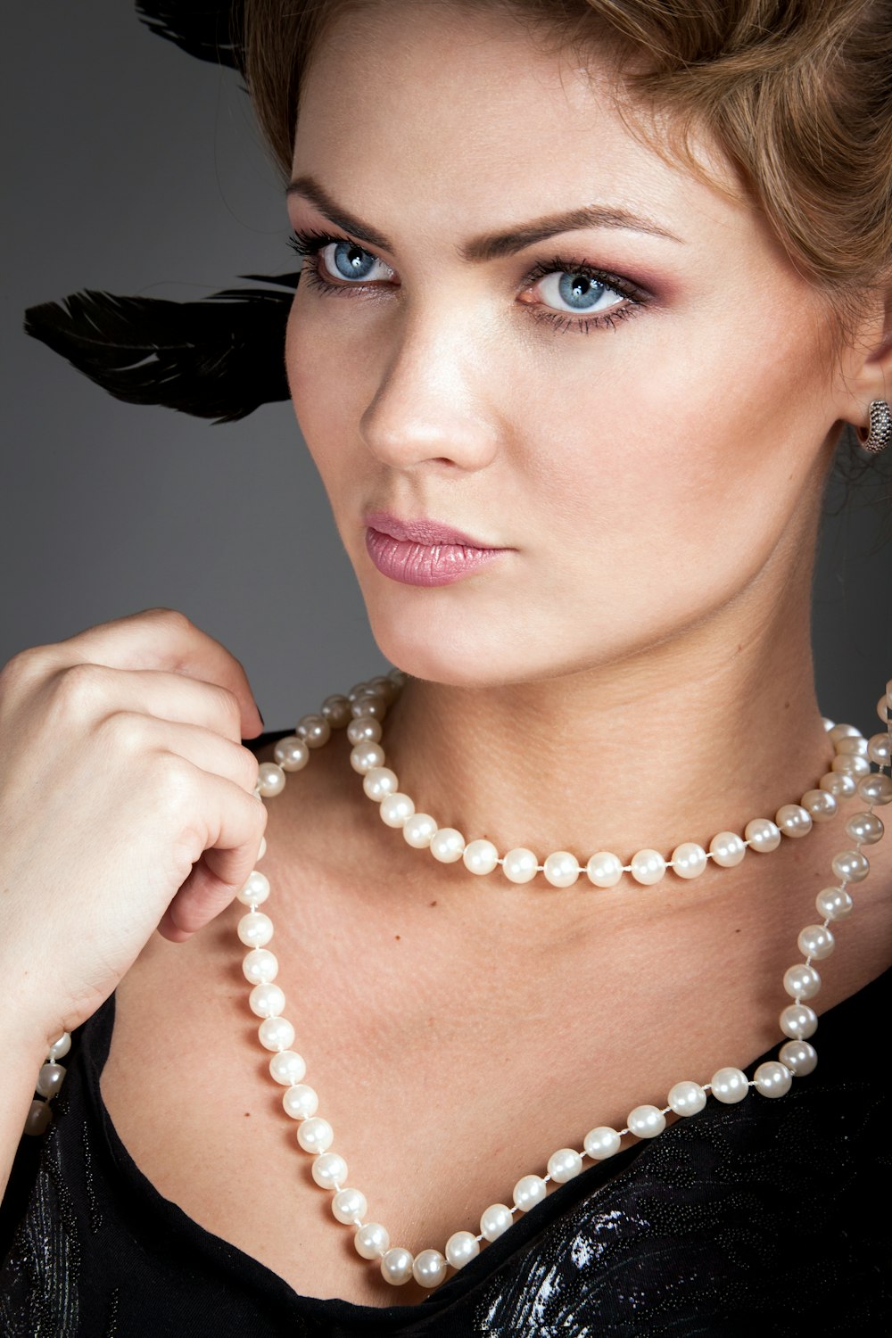 Frau hält ihre weiße Perlenkette