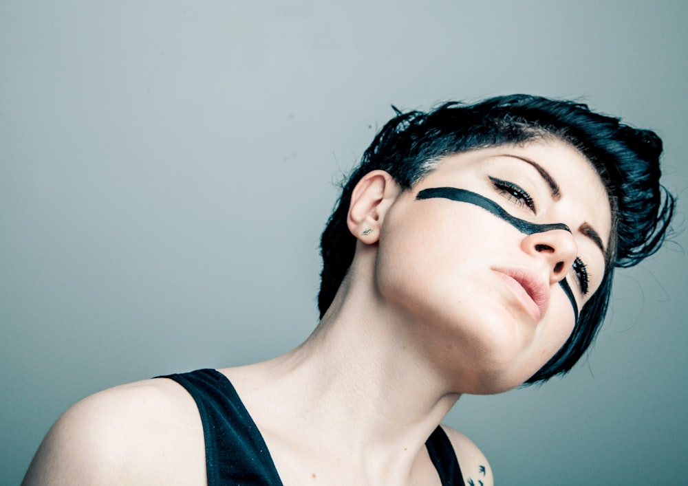 woman wearing black tank top with black paint on her face