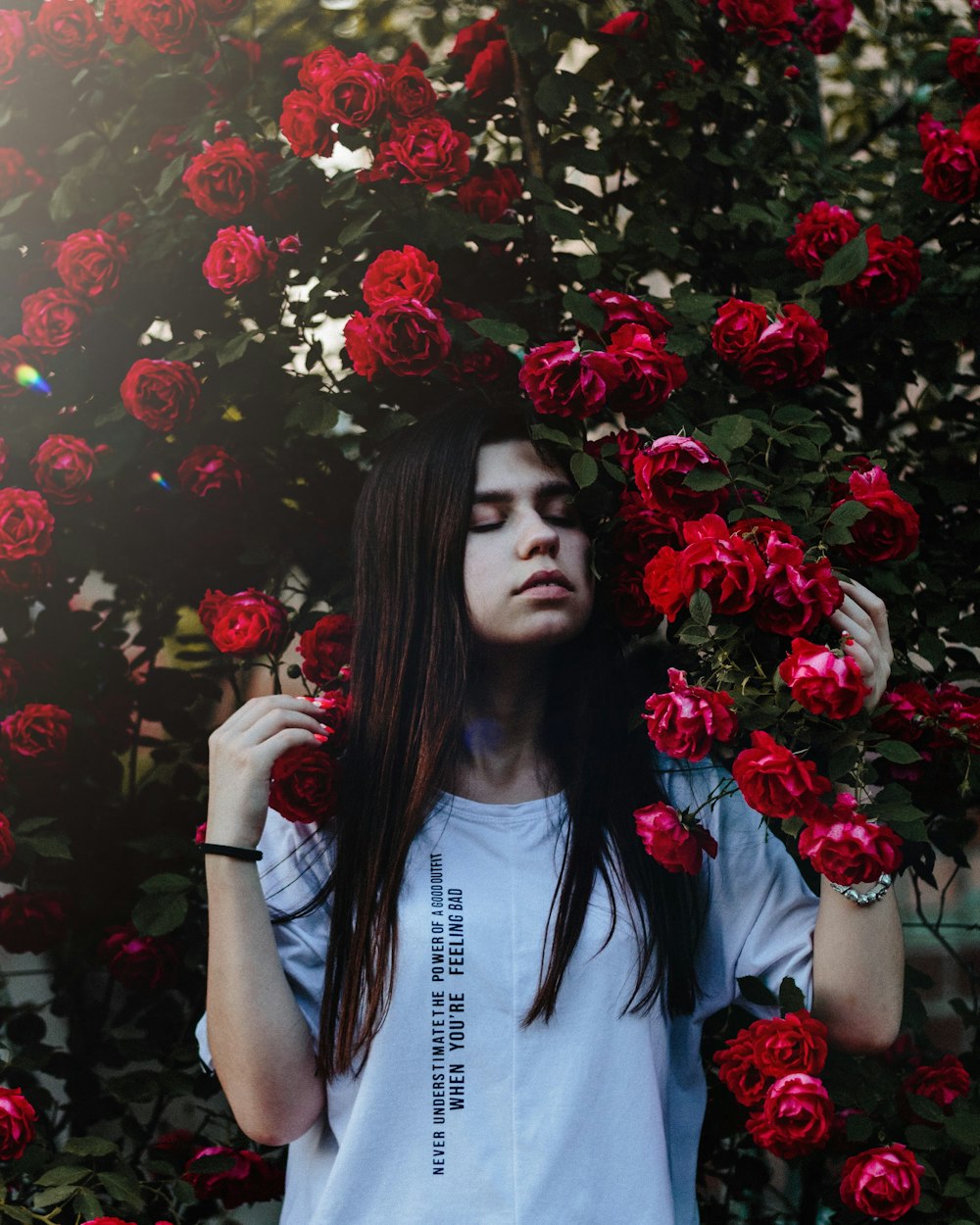 woman wearing grey shirt beside red rose flowers