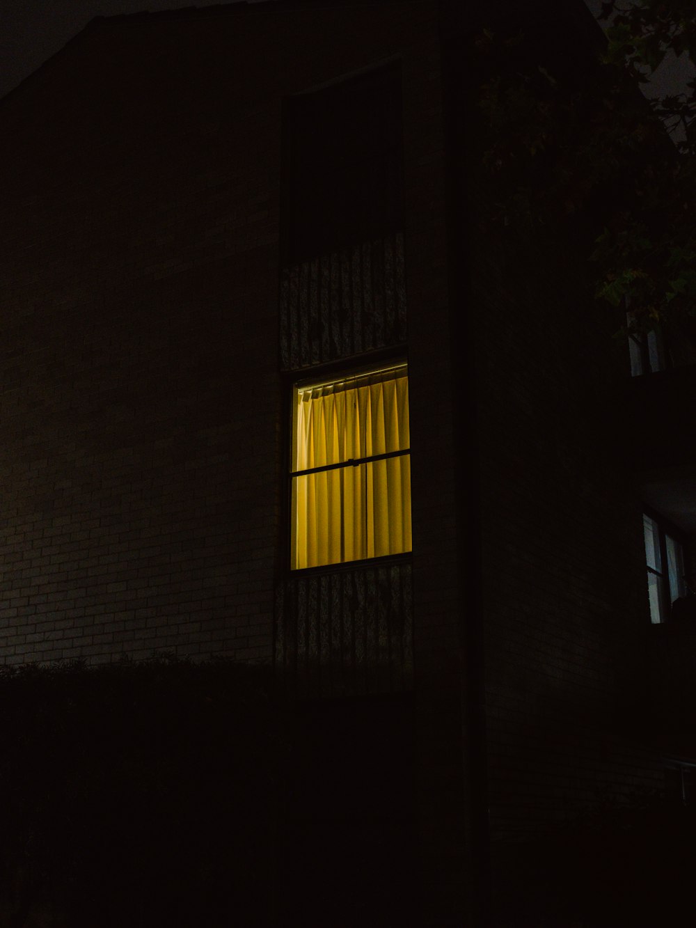 Un edificio oscuro con una ventana iluminada por la noche