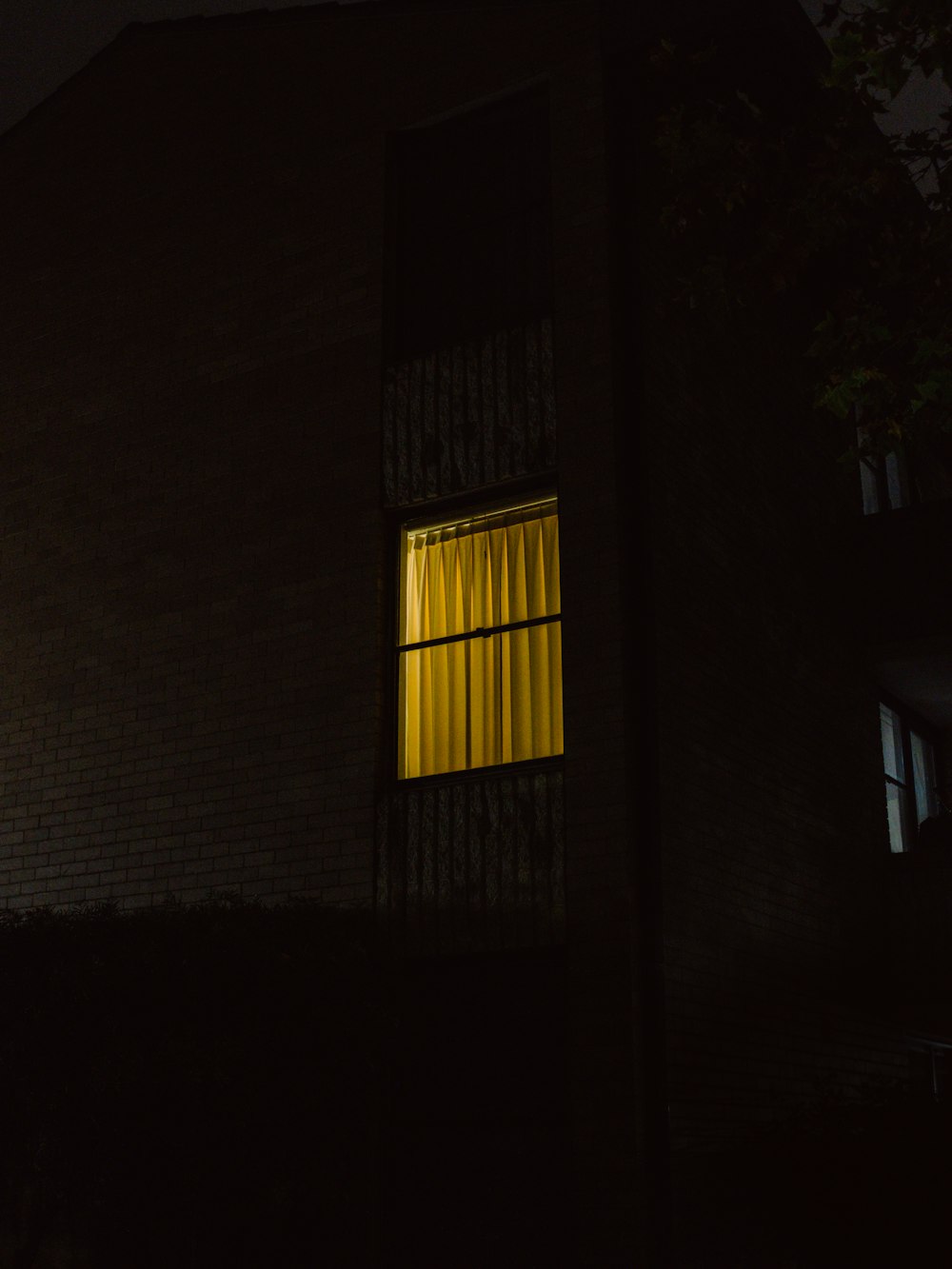 a dark building with a window lit up at night