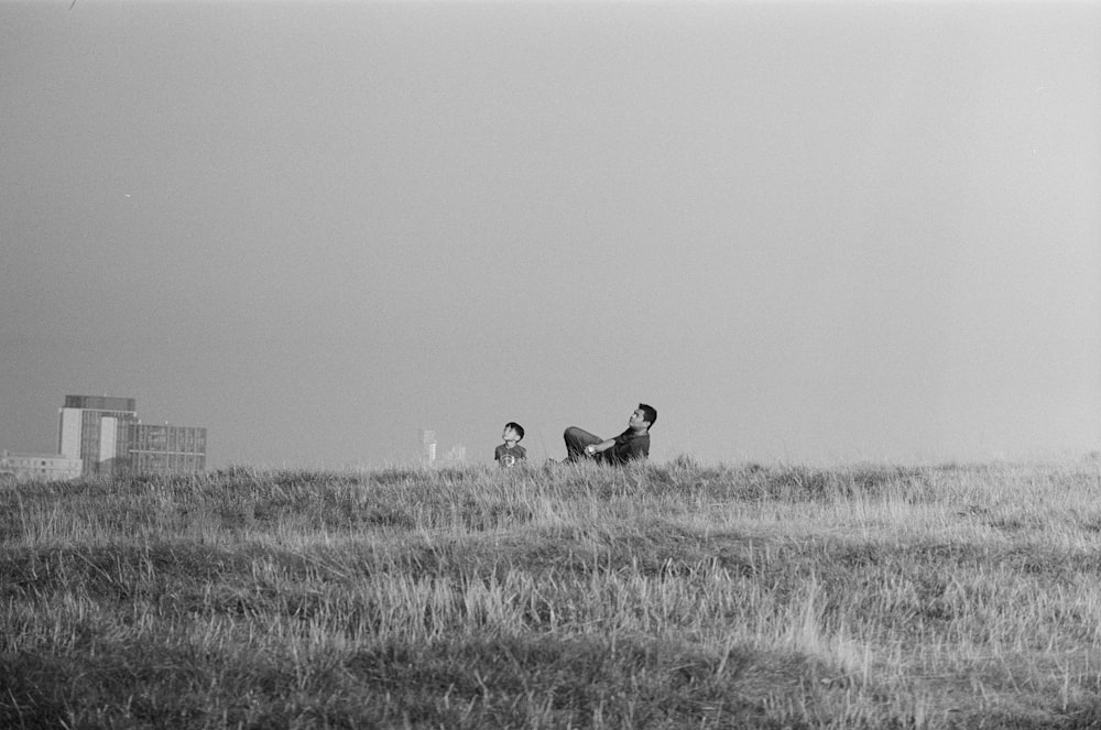 man lying and boy sitting on grass