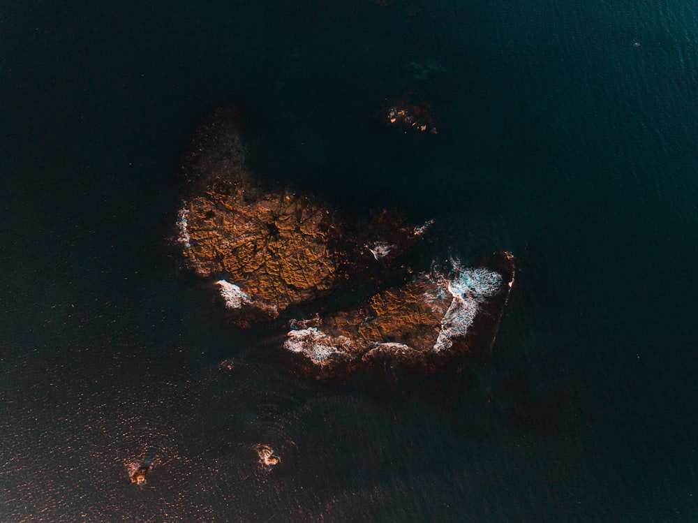 aerial photography of brown rock formation near body of water