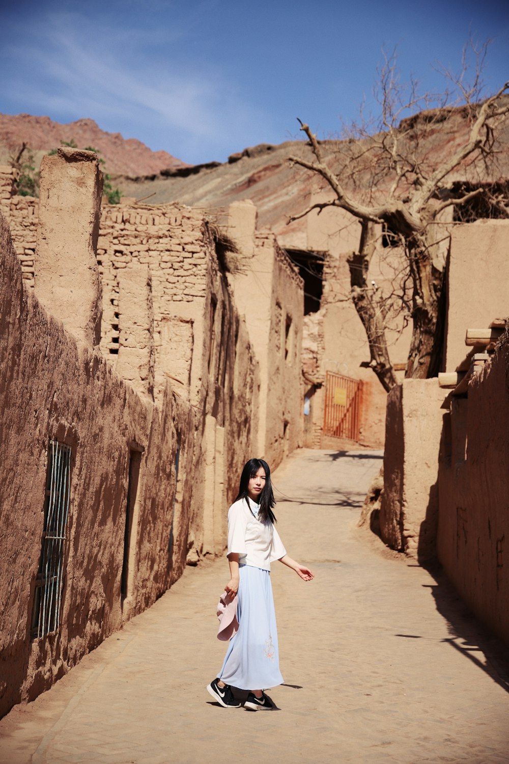 woman standing at middle of walkway surrounded by concrete wall