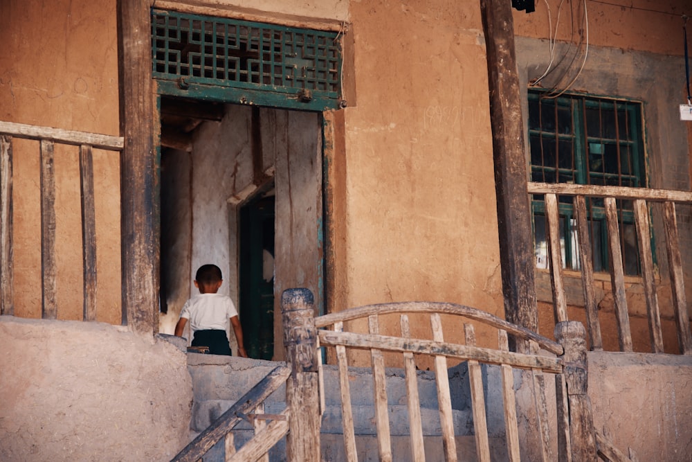 boy in white shirt and black bottoms standing inside house