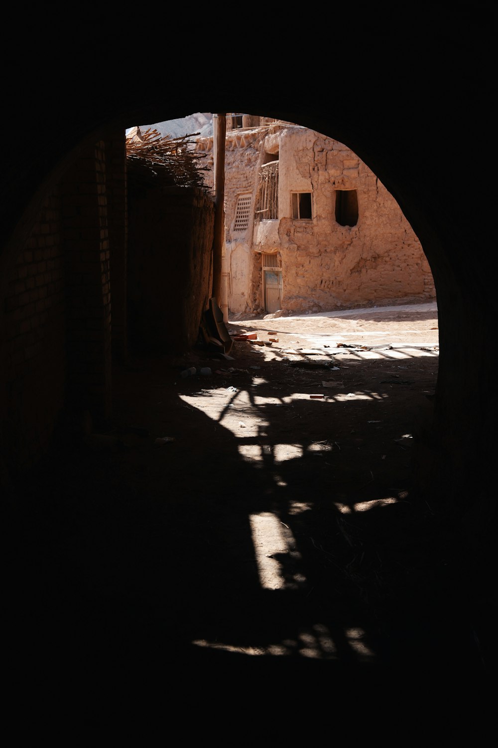 a dark tunnel leading to a building with a clock on it