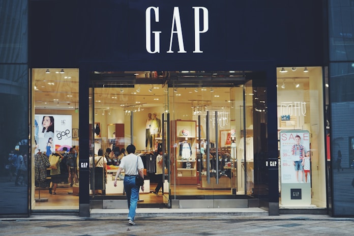 person in white shirt and blue jeans walking inside GAP store