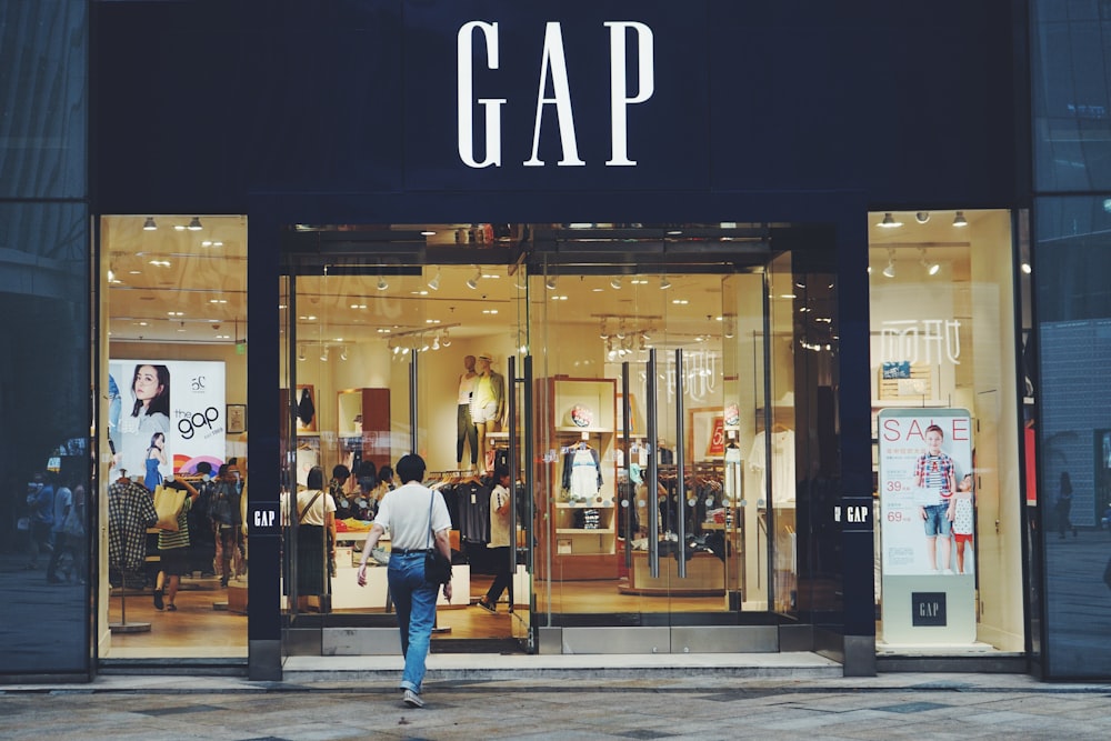 person in white shirt and blue jeans walking inside GAP store