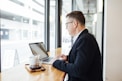 man using MacBook facing wall