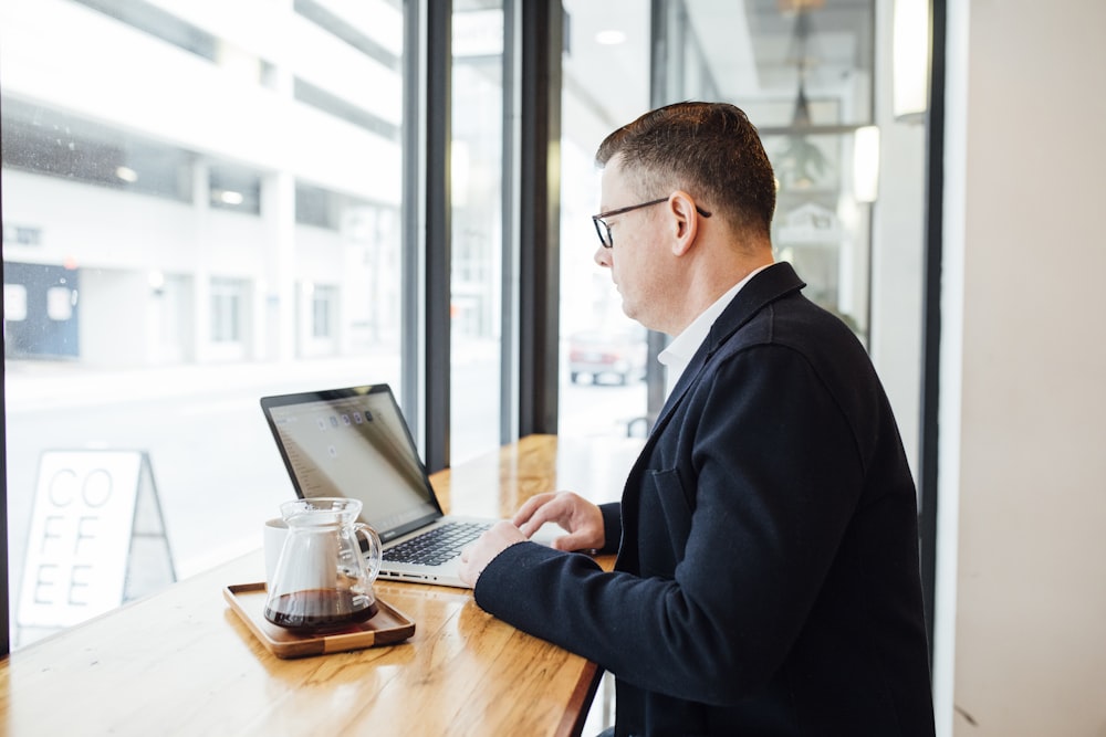 man using MacBook facing wall