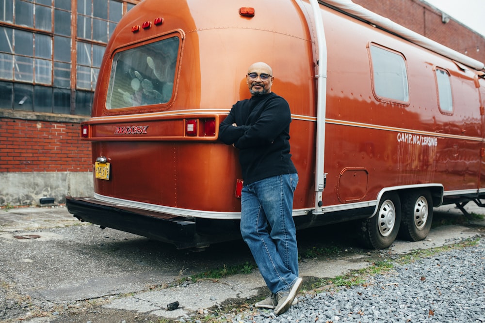 man leaning beside red vehicle