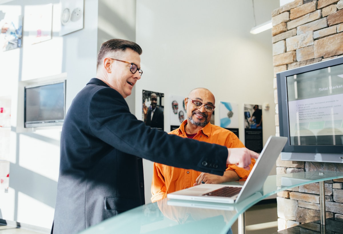 Two B2B colleagues discussing outreach and engagement over a laptop in a modern office
