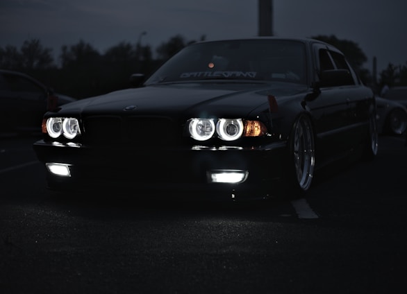 A sleek black car with neon green tinted windows parked under city lights, showcasing a flawless finish.