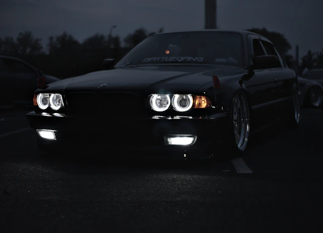 A sleek, shiny black car reflecting city lights at dusk, showcasing expert detailing.