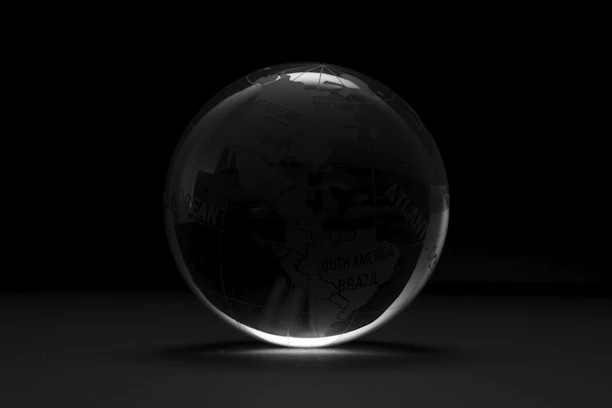 A polished, gold-accented globe with shipping containers and trade routes illuminated against a deep navy background.