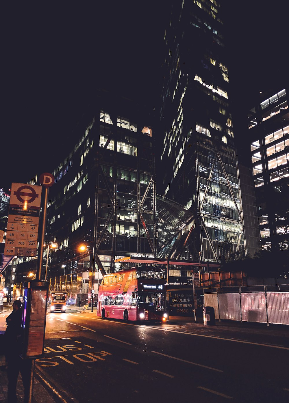 a double decker bus driving down a city street at night