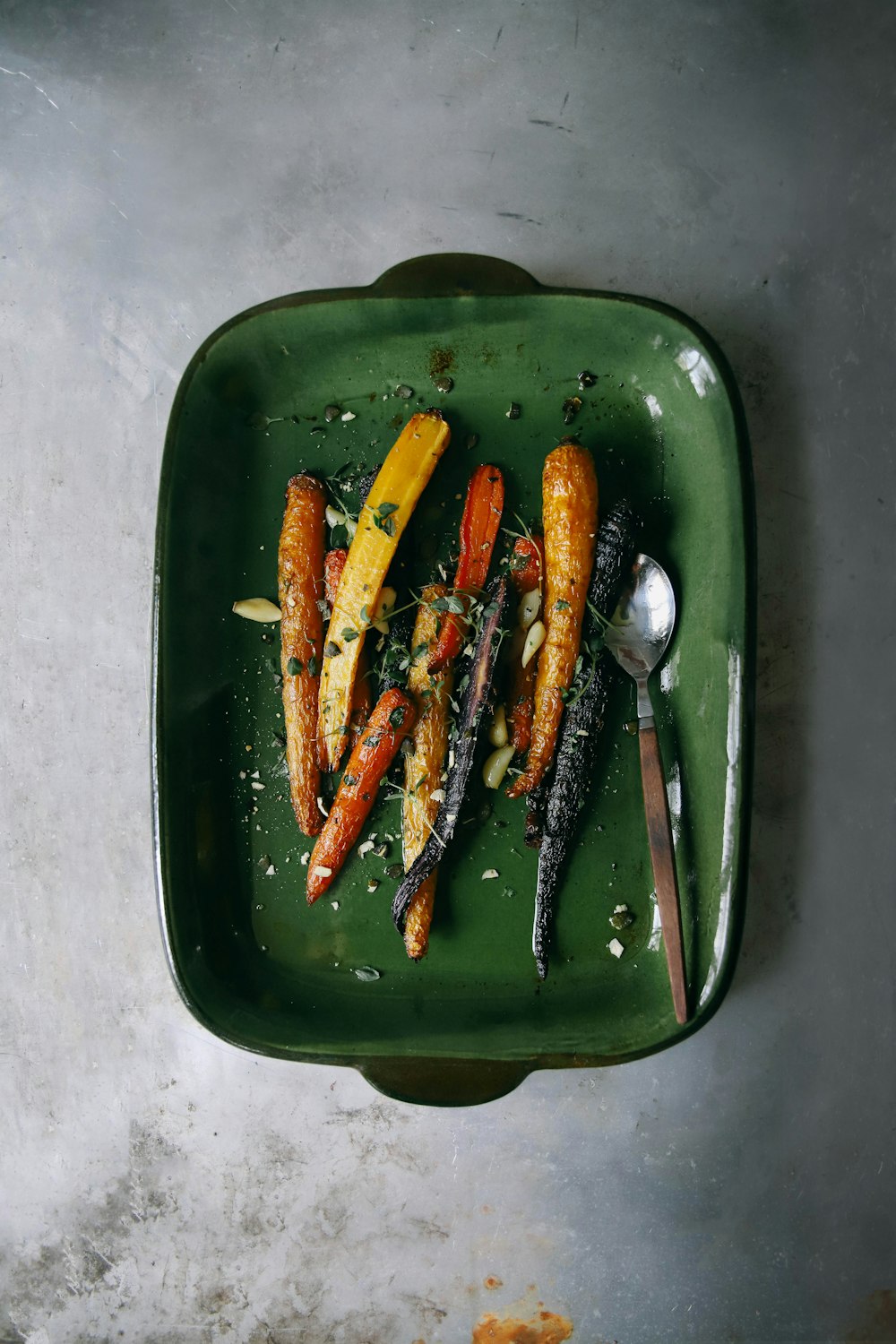 a green plate topped with carrots and other vegetables