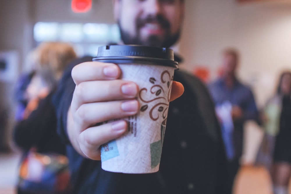 man holding white and black disposable cup