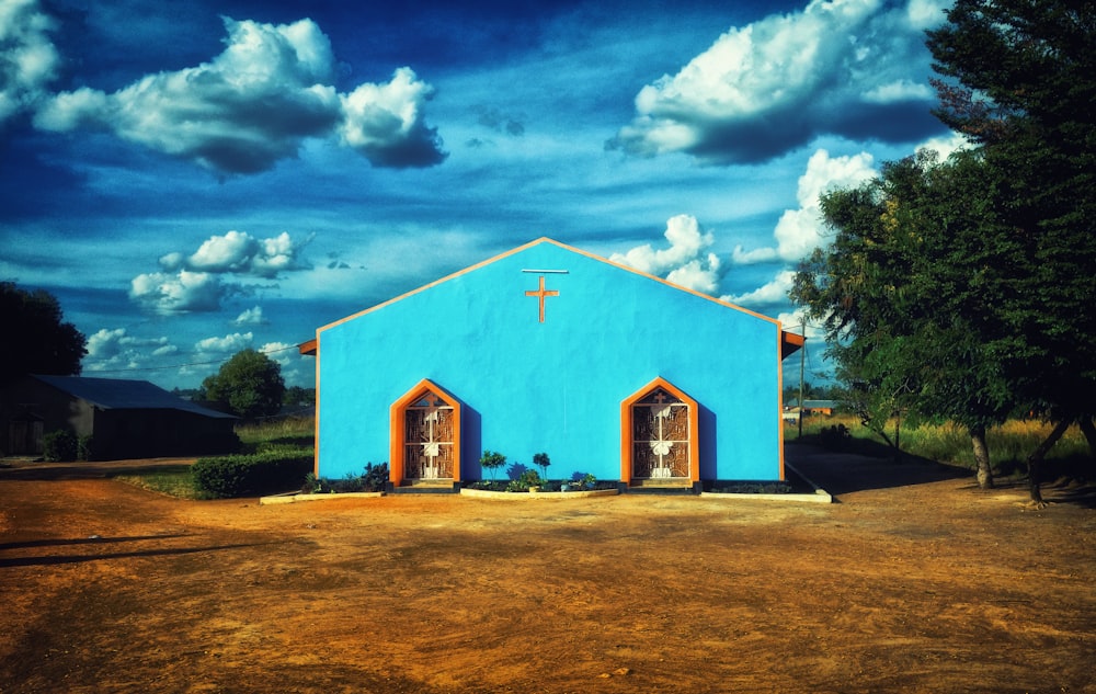 a blue building with two doors and a cross on it