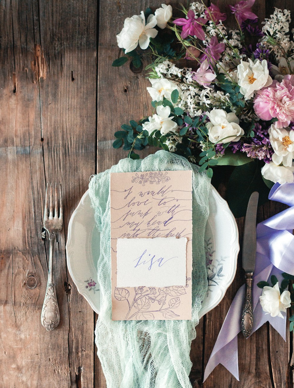 round white plate beside fork near flowers on brown wooden surface