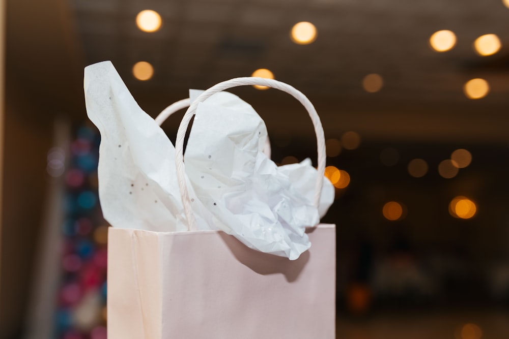 una bolsa de compras blanca con una bolsa de papel de seda encima.