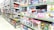 A brightly lit toy store aisle with shelves stocked with various boxed toys, including model cars, helicopters, building blocks, and plush toys. The shelves are organized with items of different shapes and colors, and the packaging features colorful designs and cartoon characters.