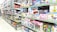 A brightly lit toy store aisle with shelves stocked with various boxed toys, including model cars, helicopters, building blocks, and plush toys. The shelves are organized with items of different shapes and colors, and the packaging features colorful designs and cartoon characters.