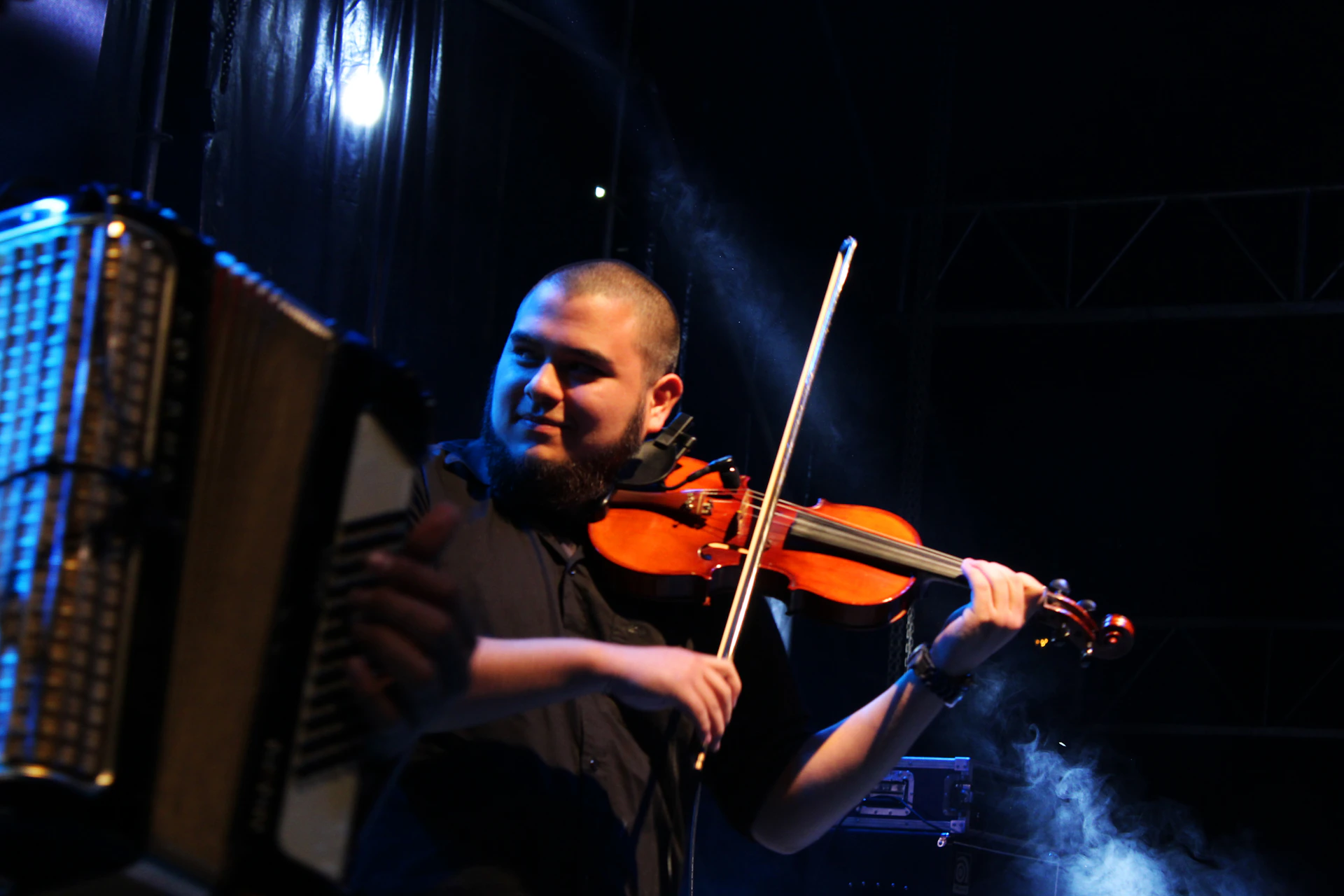 A close-up shot of Inna Dudukina passionately playing a vintage violin under warm stage lights.