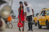A smiling couple posing beside a sleek convertible on a sunny Miami Beach street.