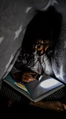 A child reading a bright, illustrated ebook under a cozy blanket fort.