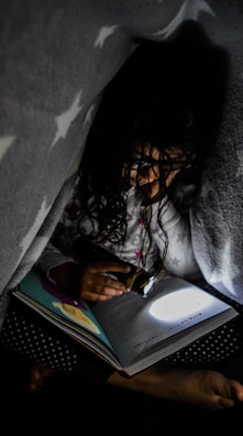 A child reading a bright, illustrated ebook under a cozy blanket fort.