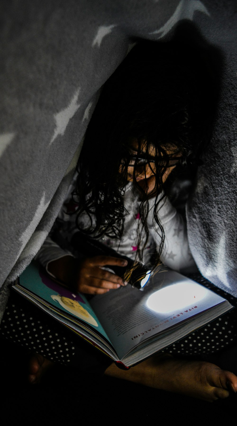 a young girl is reading a book in bed