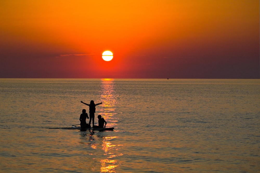 ボートの夕焼けの風景に立っている人のシルエット