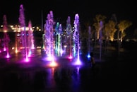 A colorful fountain display with spumeggiante water effects illuminated at night.