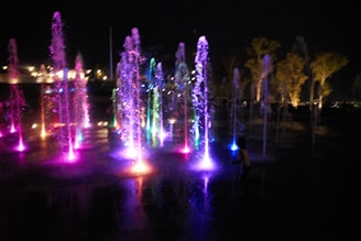 A colorful fountain display with spumeggiante water effects illuminated at night.