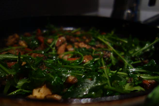 A busy chef quickly preparing a vibrant vegetable dish using pre-washed, ready-to-use greens.