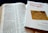 An open Bible is displayed with text visible, showing references to Corinthians. Beside it is a book titled 'How to like Paul again' by Conrad Gempf, which carries an image of an old letter with postal stamps. The arrangement suggests a reading or study setup.