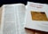 An open Bible is displayed with text visible, showing references to Corinthians. Beside it is a book titled 'How to like Paul again' by Conrad Gempf, which carries an image of an old letter with postal stamps. The arrangement suggests a reading or study setup.