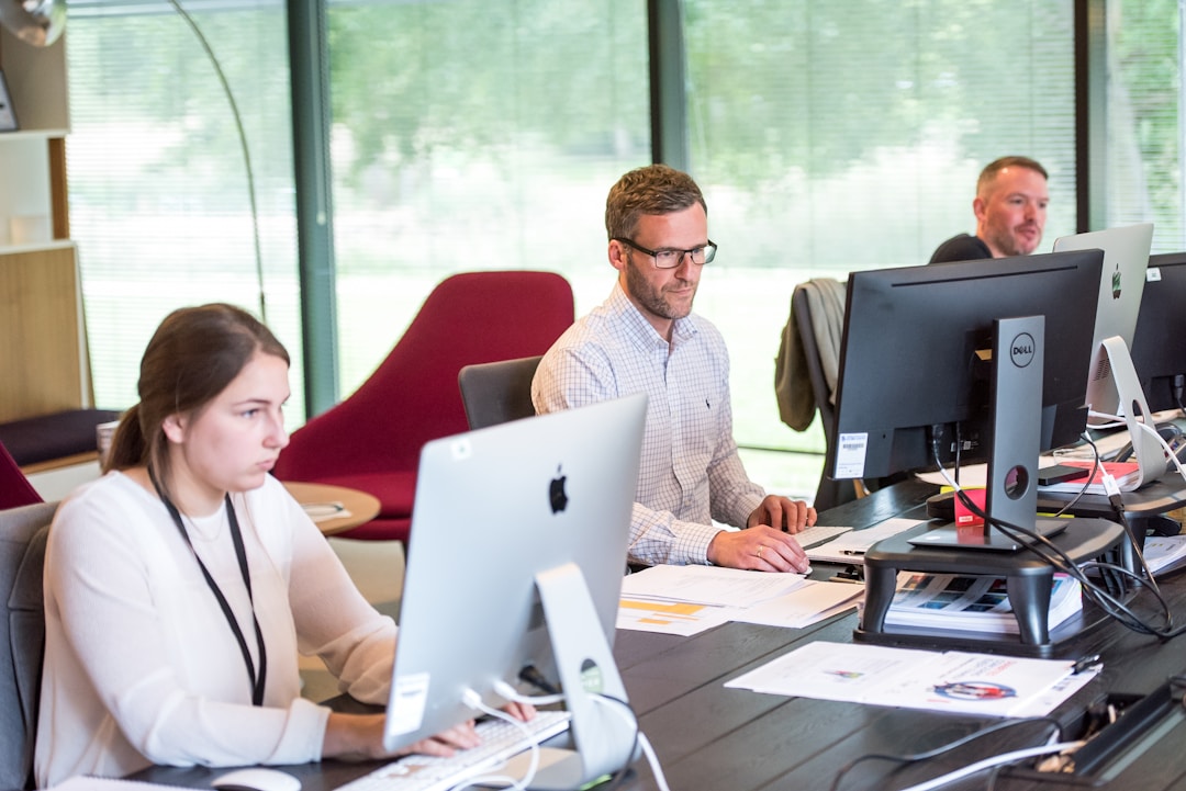 Team members in an office setting working on computers around a table, focusing on enhancing customer relationship management through data analysis