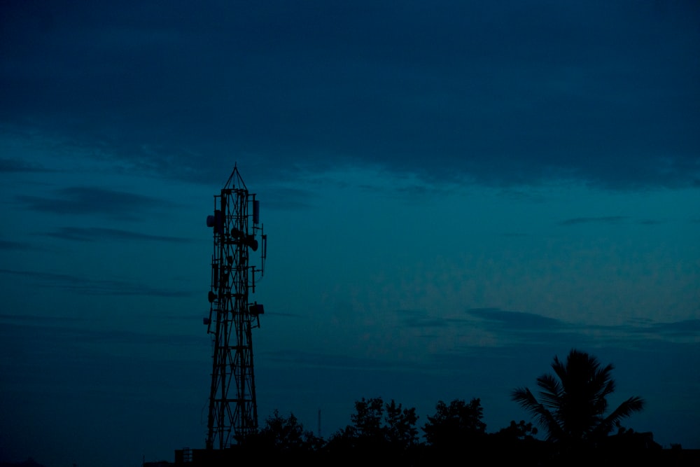 a tall tower sitting next to a forest under a blue sky